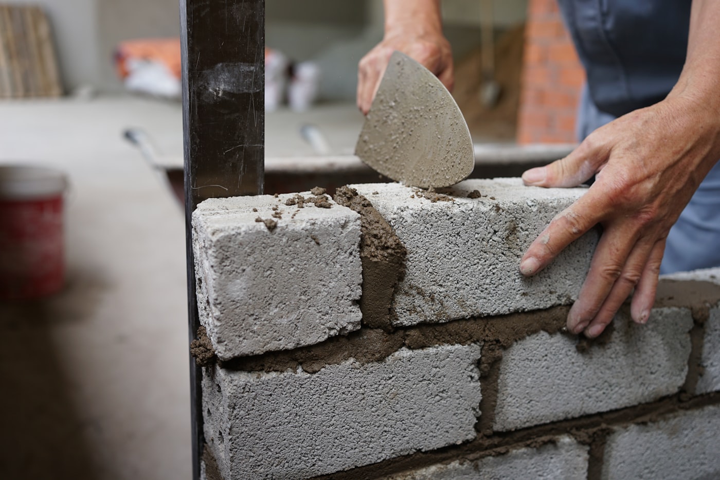 Handwerker mauert eine Wand und verstreicht Mörtel mit der Kelle