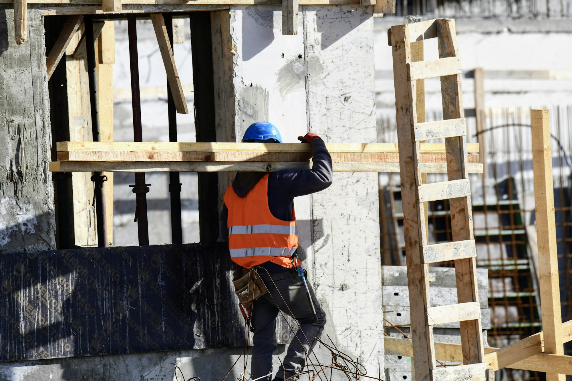 Handwerker mit Schutzhelm arbeitet an der Schalung eines Rohbaus